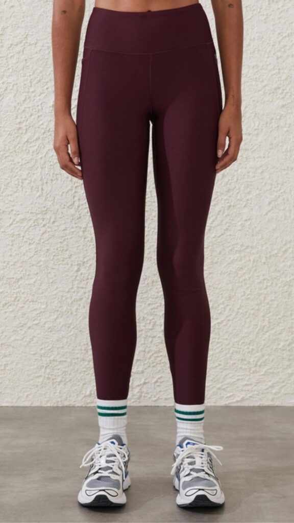 Cotton On Body Fleece Lined Full Length Tights have a mid-rsie waistband and are full length. This shade is a rich burgundy worn with white socks with emerald green stripes and white and grey sneakers for a trendy, sporty look. 