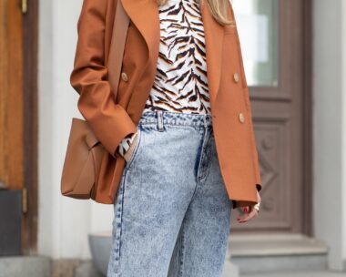 Acid wash jeans with a tan jacket and animal print blouse.