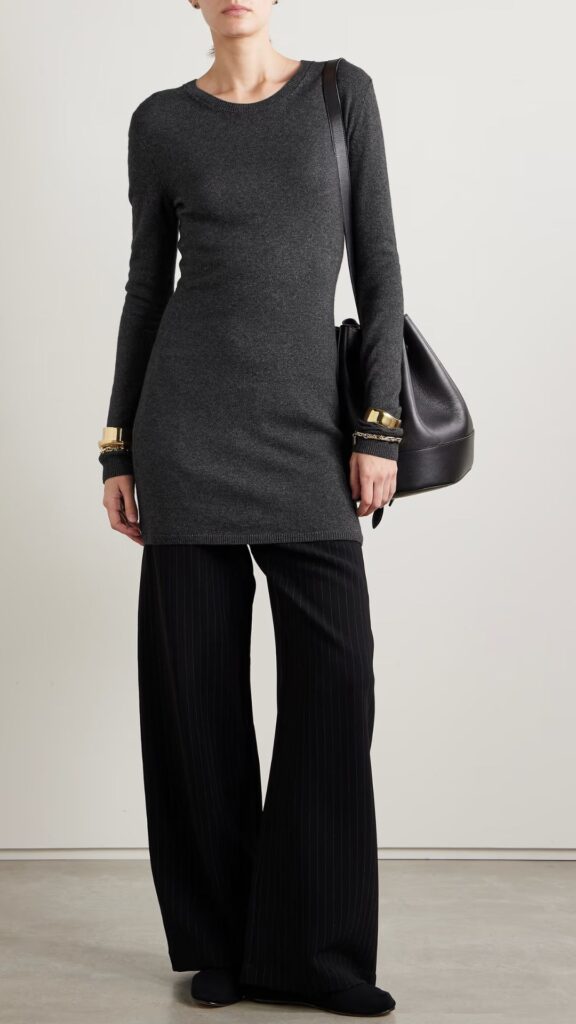 This asphalt grey, figure hugging mini knit dress with long sleeves is worn over loose, flared black pants with gold cuff jewellery. 