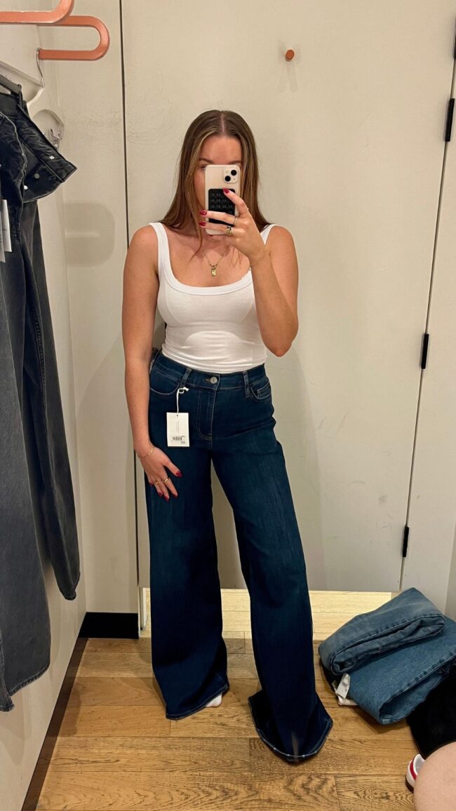woman wears blue jeans and white tank