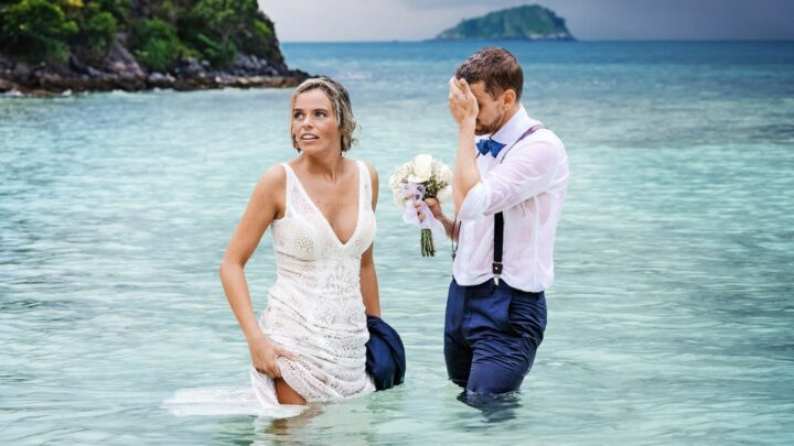 a blonde woman and a man stand in the water in a promo shot for reality tv series stranded on honeymoon island