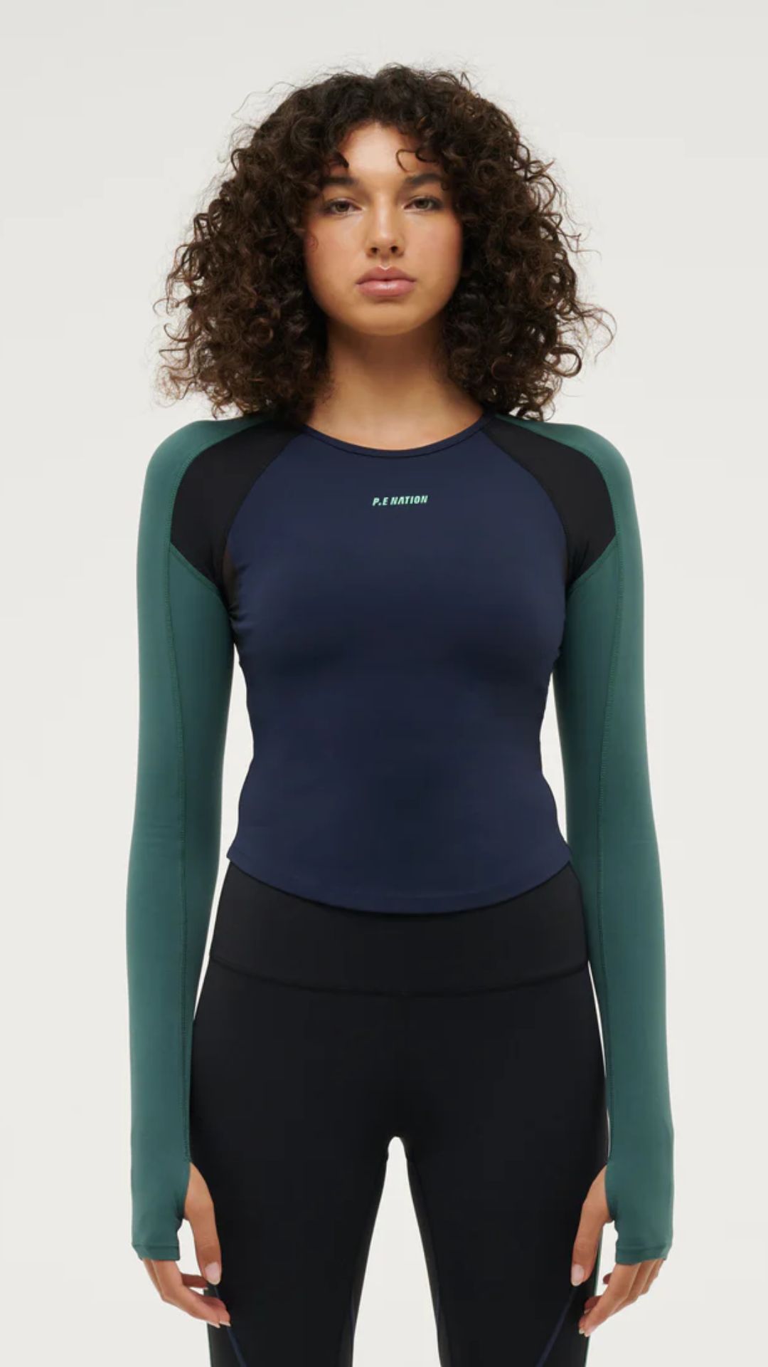 a woman with brown curly hair wears a navy and green Long-sleeve Women's Activewear Top