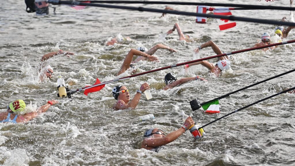 Italy's Rachele Bruni (C) takes refreshment at a feed station along the course during the women's 10km marathon swimming event during the Tokyo 2020 Olympic Games at the Odaiba Marine Park in Tokyo on August 4, 2021.