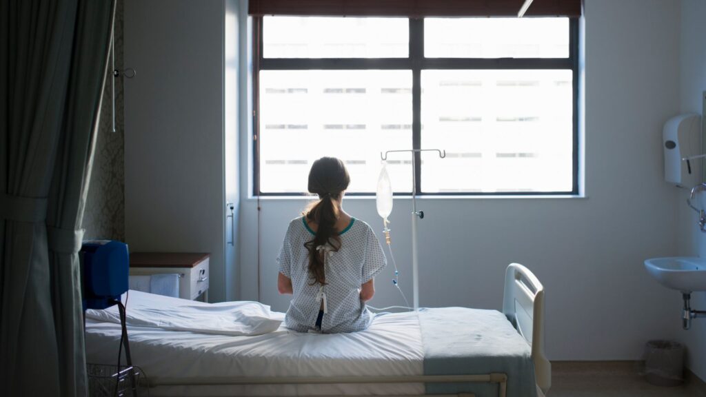 woman sitting in a hospital bed staring out window