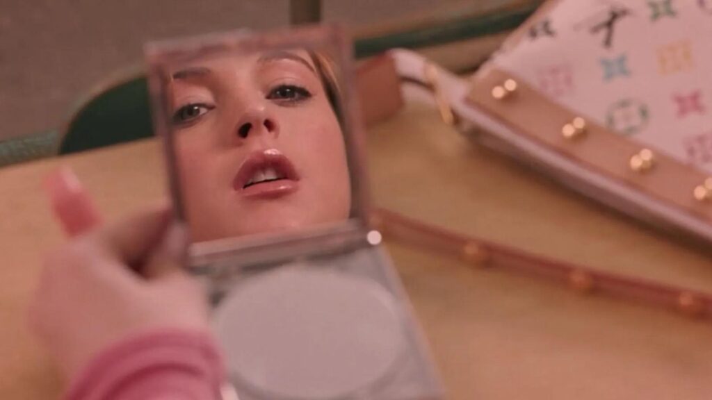 Lindsay Lohan in Mean Girls stars into a makeup compact with a look of consternation on her face. 