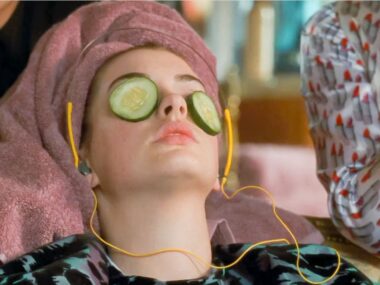 Anne Hathaway in The Princess Diaries having a self care moment with cucumber slices over her eyes, a towel wrapped around her and headphones in.