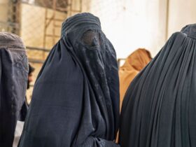 Afghan burqa-clad women stand in a queue as they wait to receive food aid from a non-governmental organisation (NGO) at a gymnasium in Kabul on January 17, 2023. - At least three leading international aid agencies have partially resumed life-saving work in Afghanistan, after assurances from the Taliban authorities that Afghan women can continue to work in the health sector. W