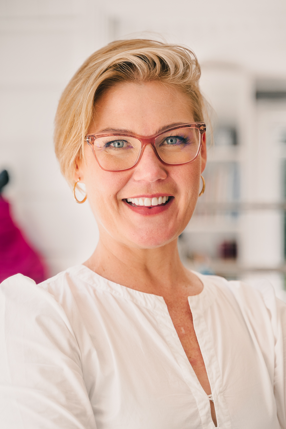 white woman blonde short hair with glasses smiling