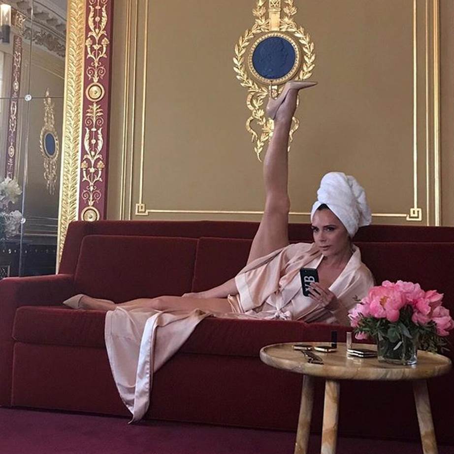 Victoria Beckham showing her flexibility with a leg raised as she lies on a lounge.